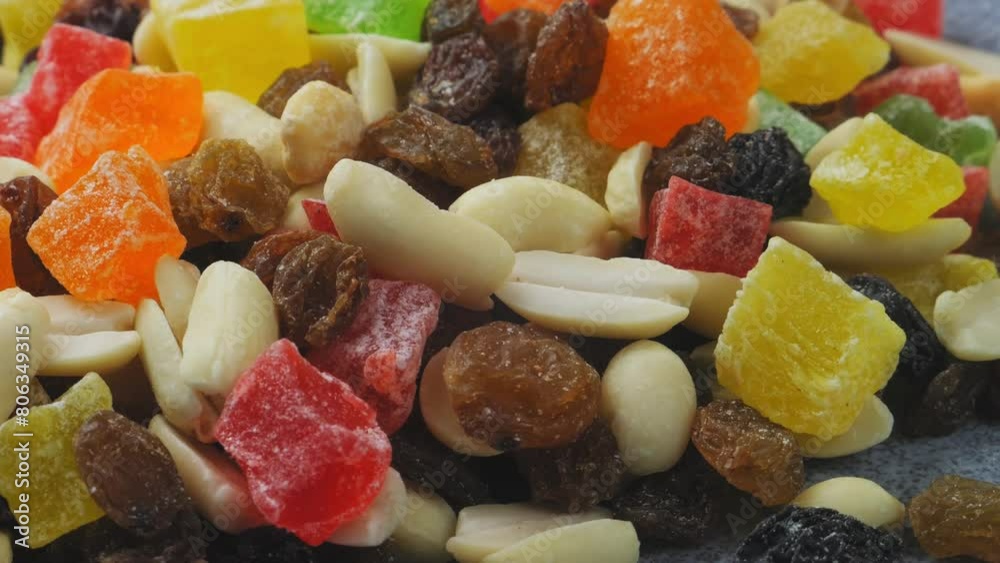 Mix of candied fruits and nuts scattered on a gray surface, rotating in a circle Mix of candied fruits and nuts scattered on a gray surface, rotating in a circle
