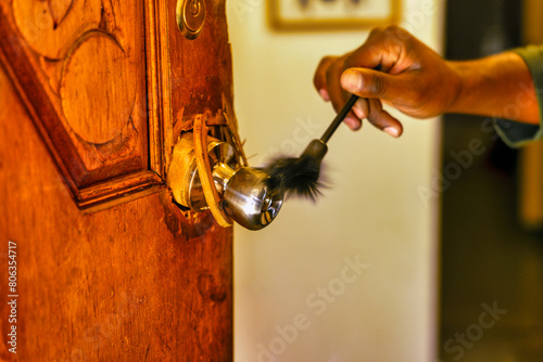 african american police detective collecting forensic evidence for fingerprints with a brush dusting off a broken door handle , fingerprint kit brush photo