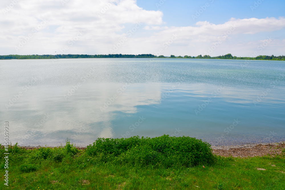 Fototapeta premium A vast lake with a lush green bank under a cloudy sky