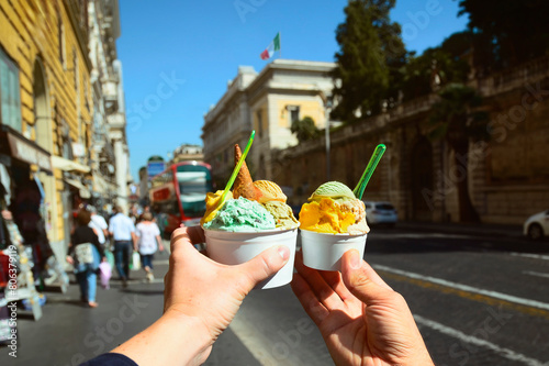 Couple with  bright  sweet Italian ice cream gelato with different flavors  in the hands  on the square in Rome, Italy