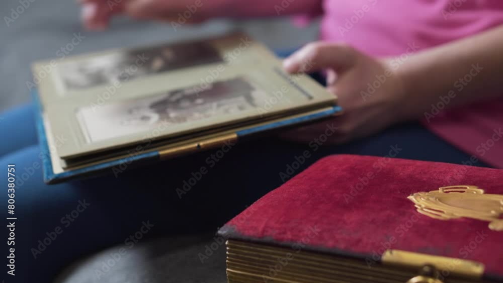 Woman is looking at an old blue photo album at home, remembers everything, that was in her youth.