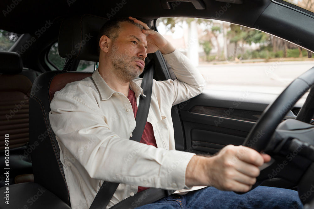 Thoughtful tired man driving car, stuck in traffic, pensive male driver with fasten seat belt looking at road, leaning on his hand Thoughtful tired man driving car, stuck in traffic, pensive male driver with fasten seat belt looking at road, leaning on his hand