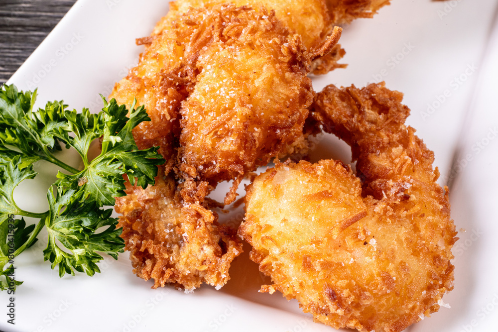 © SockaGPhoto - Close up of a plate of deep fried coconut shrimp with a red dipping sauce