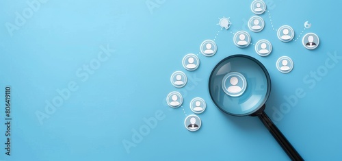 Photo of a magnifying glass over target audience icons on a blue background, showing a customer profile concept for business and marketing planning