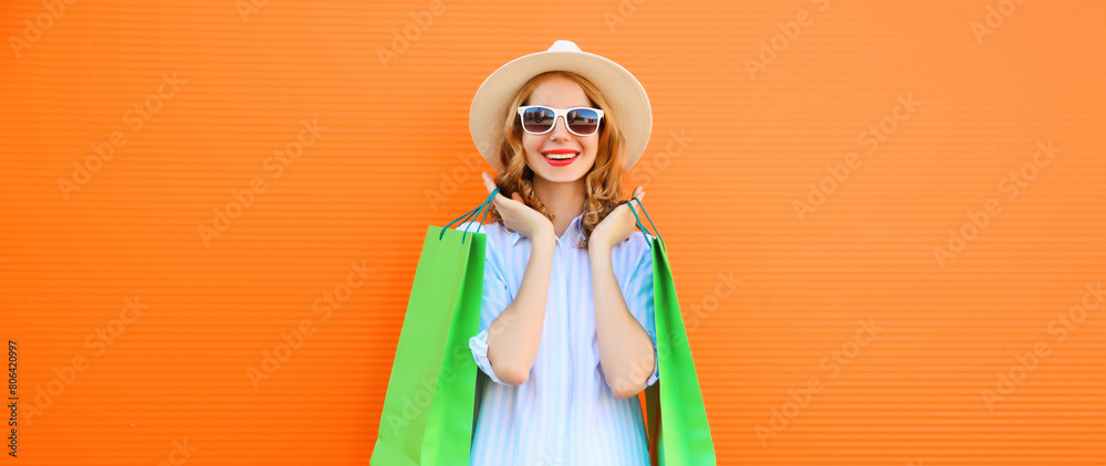 Stylish young woman model with shopping bags in summer straw hat on orange studio background Stylish young woman model with shopping bags in summer straw hat on orange studio background