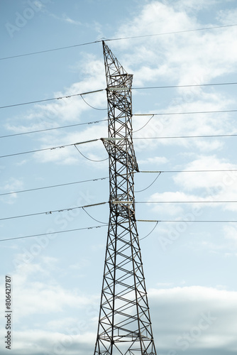 Towering Electrical Power Line Against Cloudy Sky