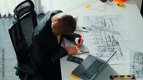 Top view of smart civil engineer drawing and measuring blueprint by using ruler. Aerial view of architect scatch building project plan at meeting table with equipment and safety helmet. Alimentation. photo