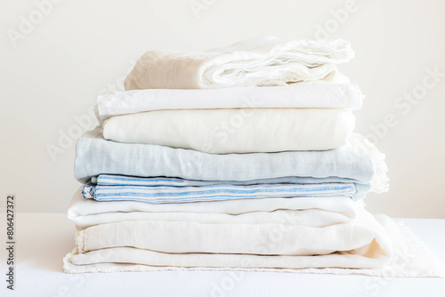 A stack of crisp, clean linens, inviting relaxation and comfort, arranged neatly against a pristine white surface.