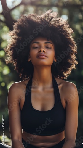 A Black woman sitting in a yoga pose with her eyes closed