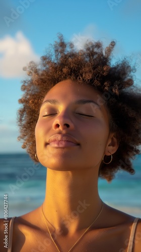 A Black woman with closed eyes meditating on the sandy beach