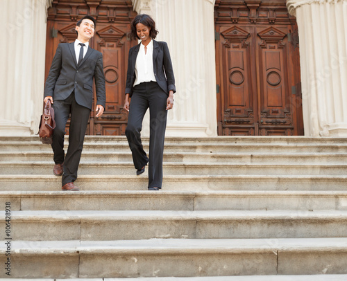 Business or legal professionals walking down courthouse steps outdoors.