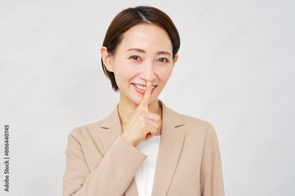 内緒のジェスチャーをするミドルエイジのビジネスウーマン　白背景