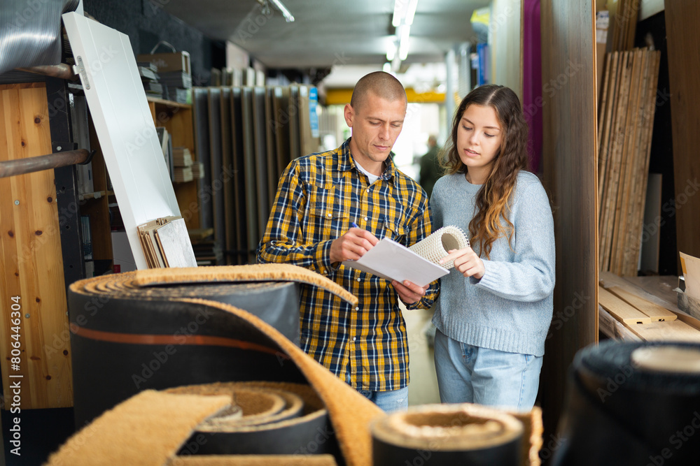 Obraz premium Married couple shopping at a hardware store checking the list on paper