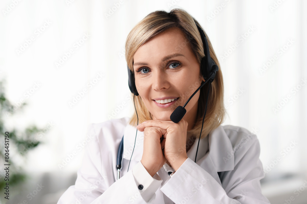 Portrait of smiling doctor in headphones having online consultation indoors Portrait of smiling doctor in headphones having online consultation indoors