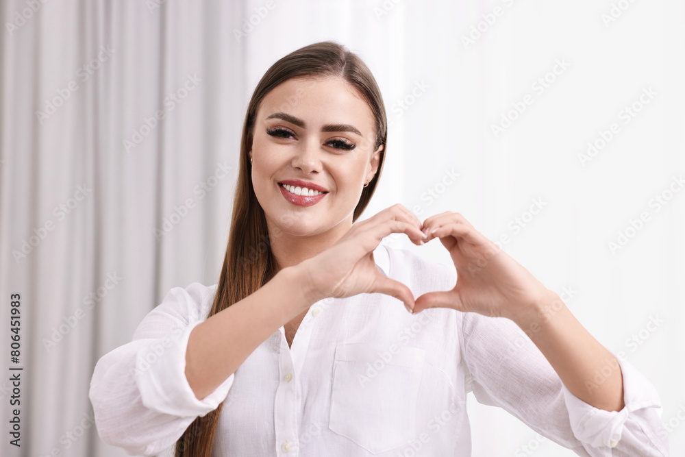 Happy woman showing heart gesture with hands indoors Happy woman showing heart gesture with hands indoors