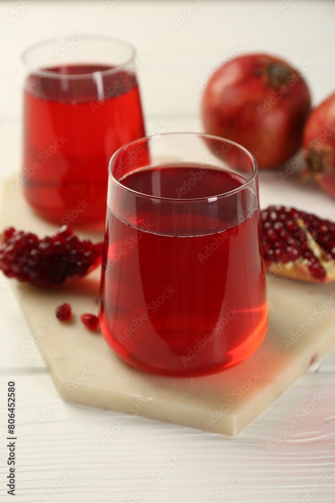 Tasty pomegranate juice in glasses and fresh fruits on white wooden table, closeup Tasty pomegranate juice in glasses and fresh fruits on white wooden table, closeup