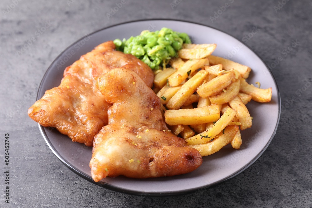 Tasty fish, chips and peas on grey table Tasty fish, chips and peas on grey table