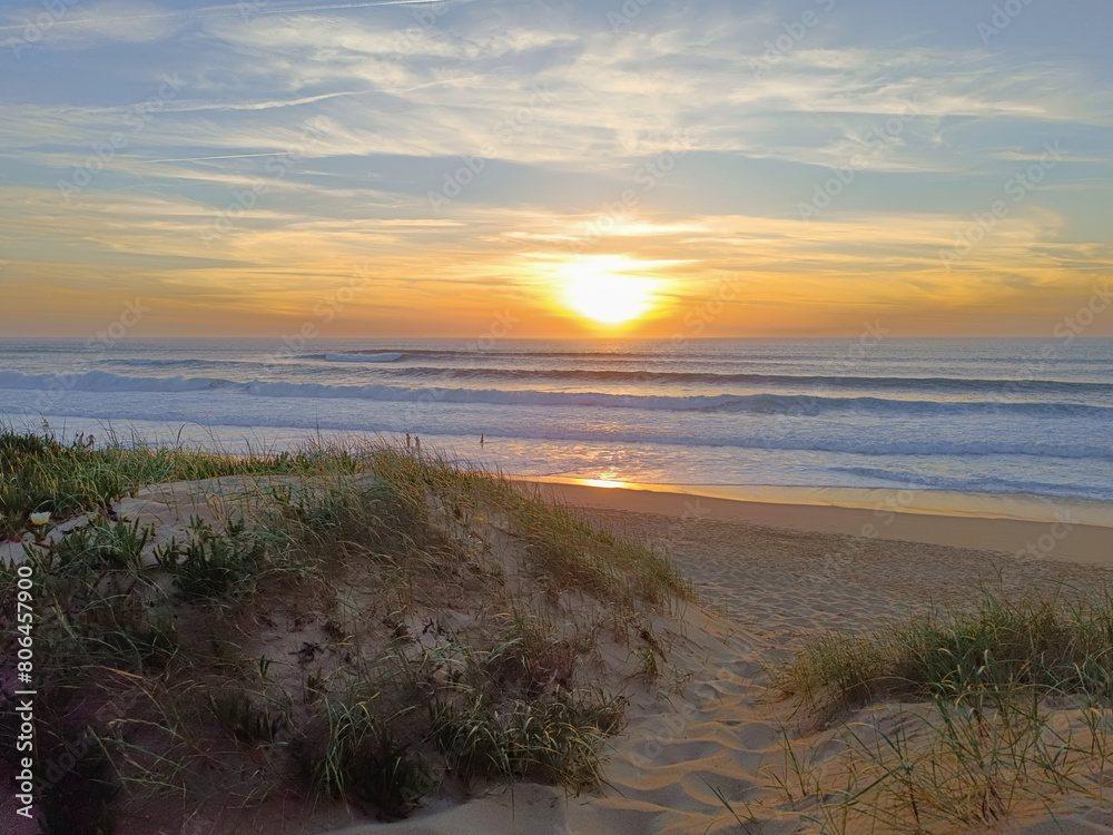 Dunes on the sand of Física beach with sunset on the horizon and reflection in the sea, Santa Cruz - Torres Vedras PORTUGAL Dunes on the sand of Física beach with sunset on the horizon and reflection in the sea, Santa Cruz - Torres Vedras PORTUGAL