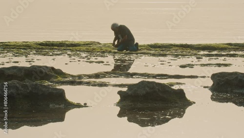Fisherman kneeling and putting bait on hook