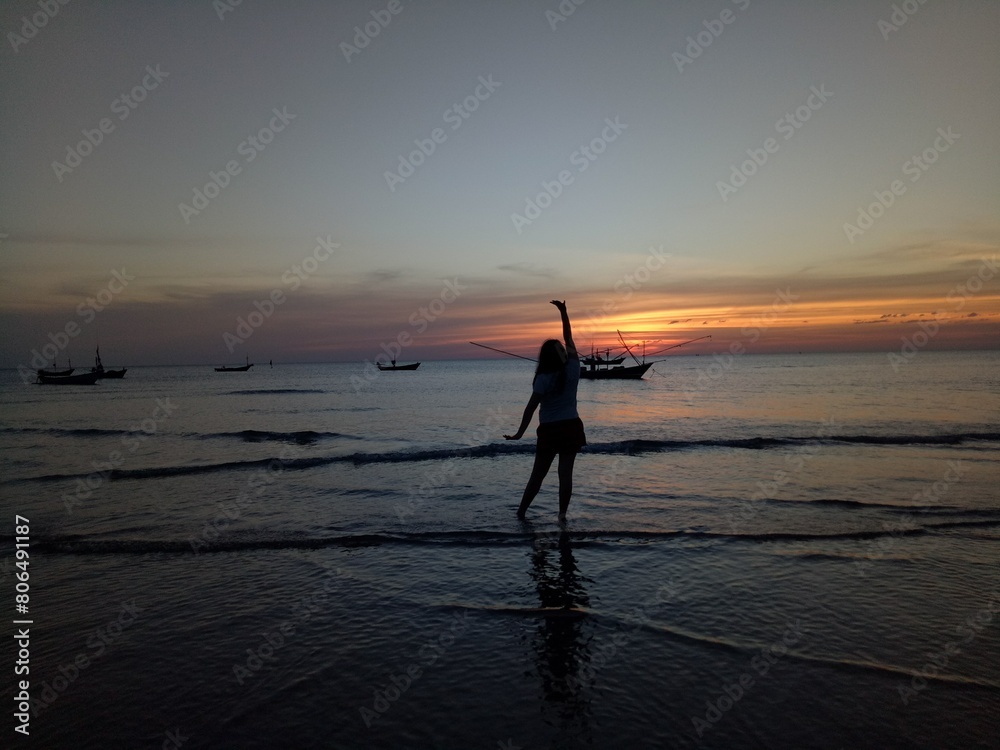 Fototapeta premium person walking on the beach at sunset