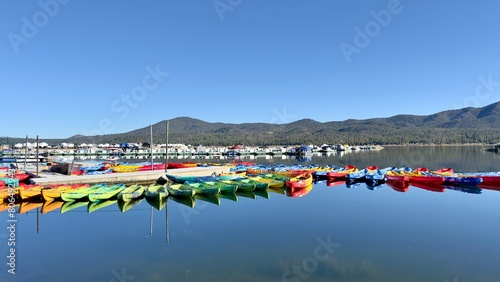 The kayak rental pier dock overlooks a serene lake surrounded by mountainous landscapes, offering a tranquil clam adventure experience. 