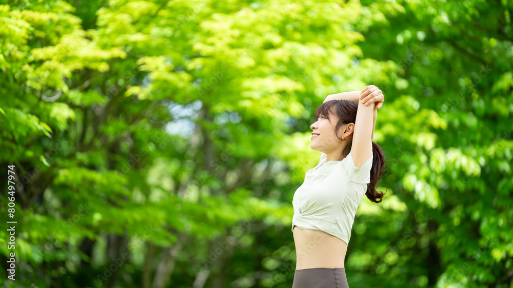 緑の中でストレッチをする笑顔の女性 緑の中でストレッチをする笑顔の女性