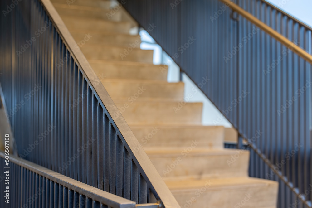 Fototapeta premium Close-up photo of a modern gray metal railing and concrete stair case between floors. 