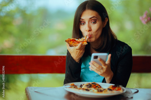 Woman Eating a Pizza while Checking her Phone. Girl being chronically online from fear of missing out 
 photo