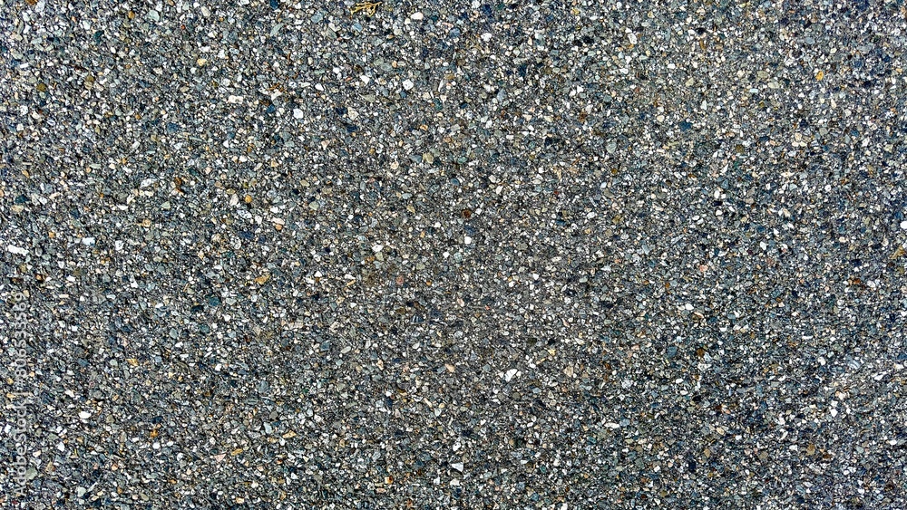 Closeup view of a compact gravel road surface, showcasing a detailed texture of interlocked stones in a durable, gritty layout. Closeup view of a compact gravel road surface, showcasing a detailed texture of interlocked stones in a durable, gritty layout.