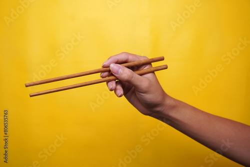 hand with chopsticks isolated yellow background