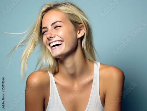 A woman with long hair is smiling and laughing while wearing color clothing