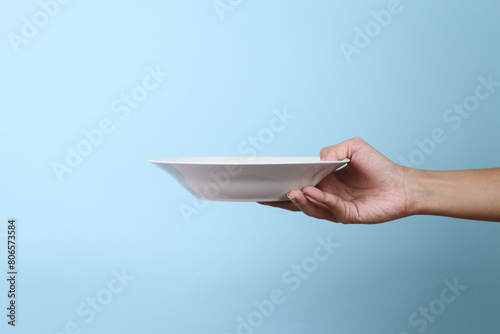 Blank plate in female hand isolated on blue background
