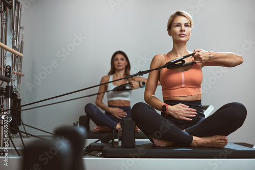 Young women exercising in a gym on pilates machines.