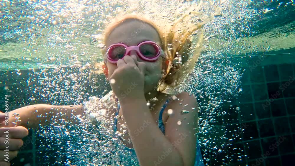 Girl swimming underwater in the pool. Cute little girl with goggles ...
