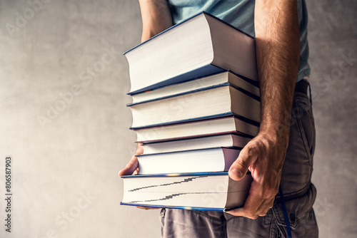 Man carrying heavy books, requiring him to put all his strength into lifting the literature