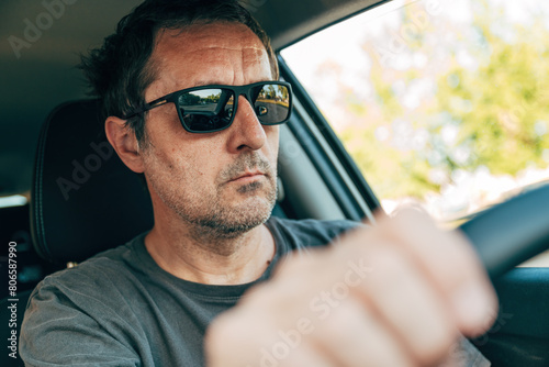 Cool mature adult male driver with black sunglasses driving a car along the road photo