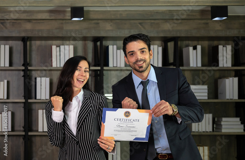 Portrait of two caucasian business woman and man in formal wear holding a certificate of appreciation recieved from business performace competition award winning in modern office. photo