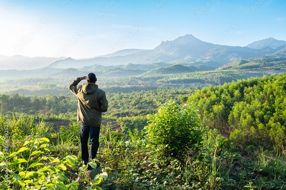 A hiker is looking at a tranquil, during sunrise in a mountainous wilderness Da Lat Vietnam