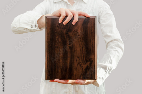 young woman holds wooden award plaque in her hands in front of her
