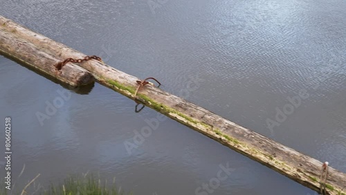 Tranquil Water Scene with Aged Wooden Log and Rusty Chains