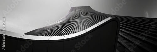 Black and white photo of a curved skyscraper, Modern architecture in a low angle shot of the building.