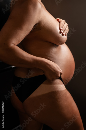 Pregnant woman pulls back her panties showing instant tan. Vertical photo. 