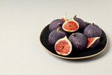 Fresh ripe figs in black bowls on white background