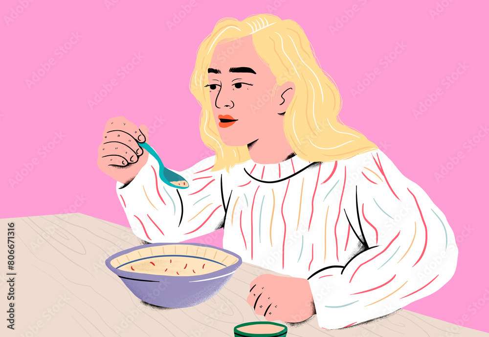 Woman enjoying soup with blue spoon at table in front of pink background Woman enjoying soup with blue spoon at table in front of pink background