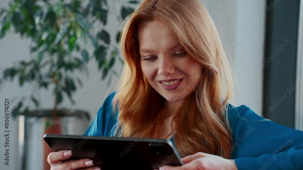 Smiling redhead businesswoman in modern office using tablet Smiling redhead businesswoman in modern office using tablet