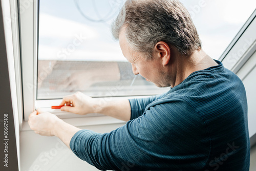 Man installing blinds on window at home photo
