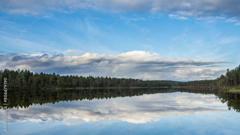 Finland, Lapland, Clouds and forest reflecting in clear lake
