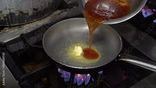 Melting a piece of butter in a frying pan. Pouring traditional peruvian sauce in a frying pan with butter. Tradituonal peruvian food praparation. photo