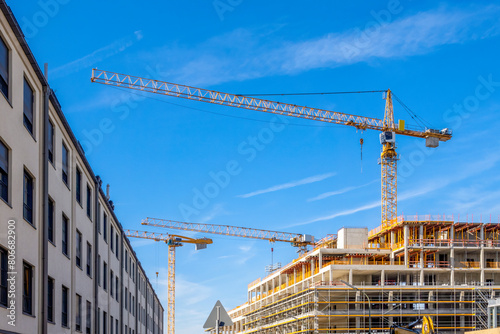 Germany, Bavaria, Munich, Industrial cranes looming over construction site photo