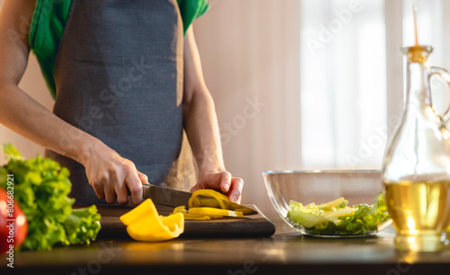 Woman cutting yellow bell pepper in kitchen at home photo